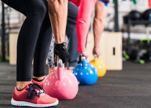 Line of people in functional fitness training group lift kettlebells.