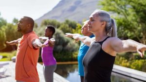 Group of seniors in outdoor exercise class outstretch arms