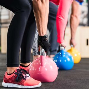 A line of people in an exercise class lifting kettlebells