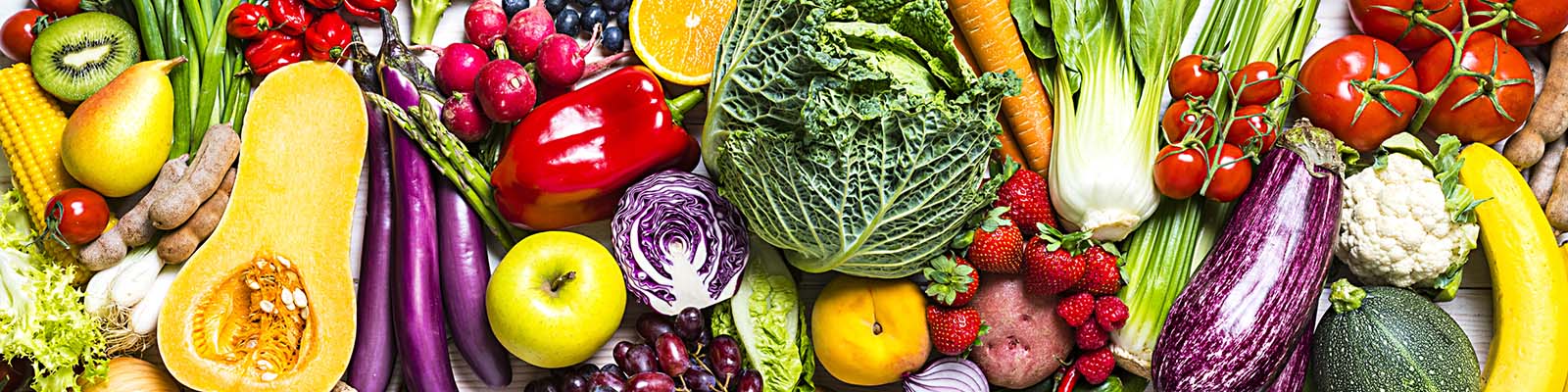 Fresh organic fruits and vegetables in a row shot from above on white tablecloth